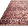 Close-up angled edge view showing Loren rug's intricate border with red, blue, and beige floral details