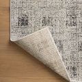 Rug corner flipped up to show woven backing and underside color contrast with grey patterned top