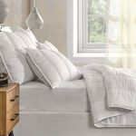 side close-up of quilt and pillows on bed near window, highlighting soft folds and serene bedroom ambiance