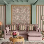 Living room with Friendship Garden Sage wallpaper framed on wall behind mauve sofa with striped green and pink cushions