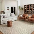 Polly Antique Mist rug styled in a living room with sofa, leather chairs, and decorative shelving