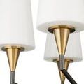 Close-up detail of white conical shade with brushed brass socket and dark metal arm supporting it