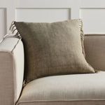 Sage linen pillow styled on beige sofa cushion, showing room context and cozy placement