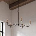 Chandelier hanging under wood ceiling beams near a window with textured white wall background