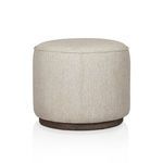 Rounded ottoman showing side view with vertical seam and burlap-like textured fabric
