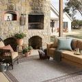 Easton Dove side rug styled in outdoor patio with wicker chairs and stone fireplace