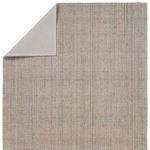 Back view showing solid beige fabric rug backing with corner folded to display texture contrast.