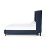 Side profile of bed highlighting high winged headboard and sleek black legs