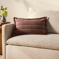 Burgundy-striped pillow styled on cream sofa in living room setting with side table and flowers