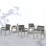Group of five Sherwood Grey armchairs arranged on light stone pavers against a white wall with tree shadows