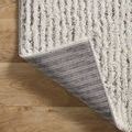 Rug corner flipped over revealing striped woven backing and finished edge