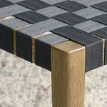 Close-up of chair seat corner with alternating black and grey woven webbing on oak frame