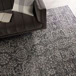 Overhead view of rug beneath dark sofa showing scale and detailed floral high-low pattern