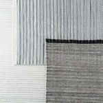 Rug placed atop a pale blue and off-white patterned layered rug to show scale and contrast.