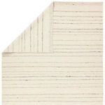 Rug corner folded over revealing woven underside with vertical taupe stripes on cream base