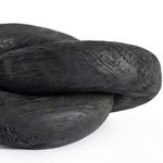 Macro detail of the joining area between knot loops highlighting the textured carbonized black wood surface