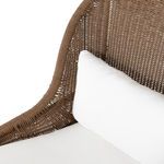 Close-up focus on white lumbar cushion set against woven fawn chair back