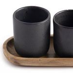 Close-up angled view showing texture and slight imperfections on the matte black espresso cups on wooden tray