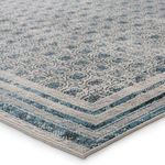 Close-up corner view showing rug's woven texture and detailed blue and gray geometric border