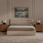 Saison painting styled on cream wall above beige upholstered bed in a softly lit bedroom interior