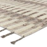 Close-up showing ribbed wool pile texture and braided fringe detail in cream and taupe tones