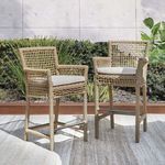 Two Brisbane outdoor stools placed on patio with concrete wall and garden backdrop