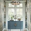 Grand Lotus Chandelier in an interior hallway with floral wallpaper, centered above blue console table