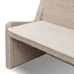 Close-up on rounded corner detailing of rattan arm with tufted beige seat cushion edge