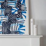 Painting and white vases on mantel with a portion of adjacent wooden bookshelf visible on right.