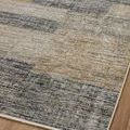 Close view of rug corner with blended rectangular patches in grey, beige, and gold hues