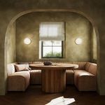 Banquette in a bright nook with arched entry, round wood table, two wall sconces, and window light