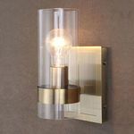 Close-up of sconce lit on textured brown wall highlighting glowing bulb and brass details