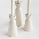 Close-up view of the off-white stoneware taper holders showing glossy texture and fine glaze details around the candle rim