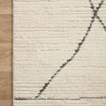Close-up of rug corner flat on wood floor highlighting pile texture and charcoal diamond lines