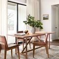 Dining room setting with rug underneath a wooden table and leather chairs near white curtains