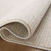 Close-up of Kamala rug folded to reveal texture and backing on hardwood floor