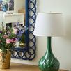 Lotus Lamp shown on wooden dresser beside gold vase with flowers and navy blue framed mirror