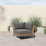 Outdoor setting with sectional chair featuring gray cushions against textured wall and greenery