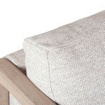 Close-up of beige cushion corner and top stitching resting against wooden armrest