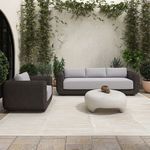 Soma sofa and matching armchair styled outdoors on beige rug against green wall foliage