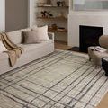 Living room scene with the rug laid out under sofa and armchair, enhancing the neutral cozy space.