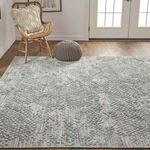 Different angled living room view emphasizing rug’s texture with rattan armchair and gray knitted ottoman