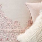 Close-up of rug edge next to pink pillow and faux fur cushion in nursery setup