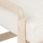 Zoomed detail on chair armrest connection to upholstered seat cushion with textured fabric.