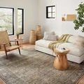 Full room view showing the rug under seating with natural light and woven décor accents