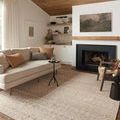 Rivers rug styled in a cozy living room with neutral sofa, dark fireplace, wood ceiling, and layered decor