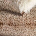 Extreme close-up showing rug’s texture, metallic spots, and base of fuzzy white chair cushion