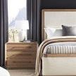 Close-up of the Form King Bed's neutral upholstered headboard and footboard with adjacent wood three-drawer nightstand and...