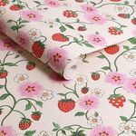 Rolled-up wallpaper showing pattern repeat and matte texture with strawberries and flowers