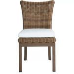 Montecito Dining Side Chair with woven rattan backrest and seat frame, white cushion, and wood-look legs
